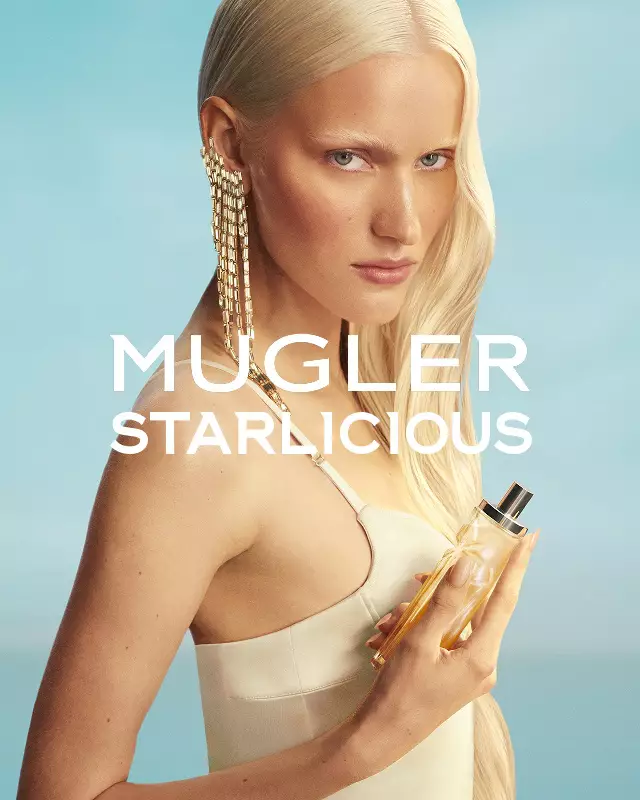 Mugler Starlicious Les Eaux Gourmandes Kampagnenbanner mit Model in hellgelbem Kleid, das den Pineapple Musk Flakon vor einem sanftblauen Himmel hält.